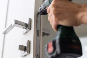 Handyman is fixing the door lock and hinges
