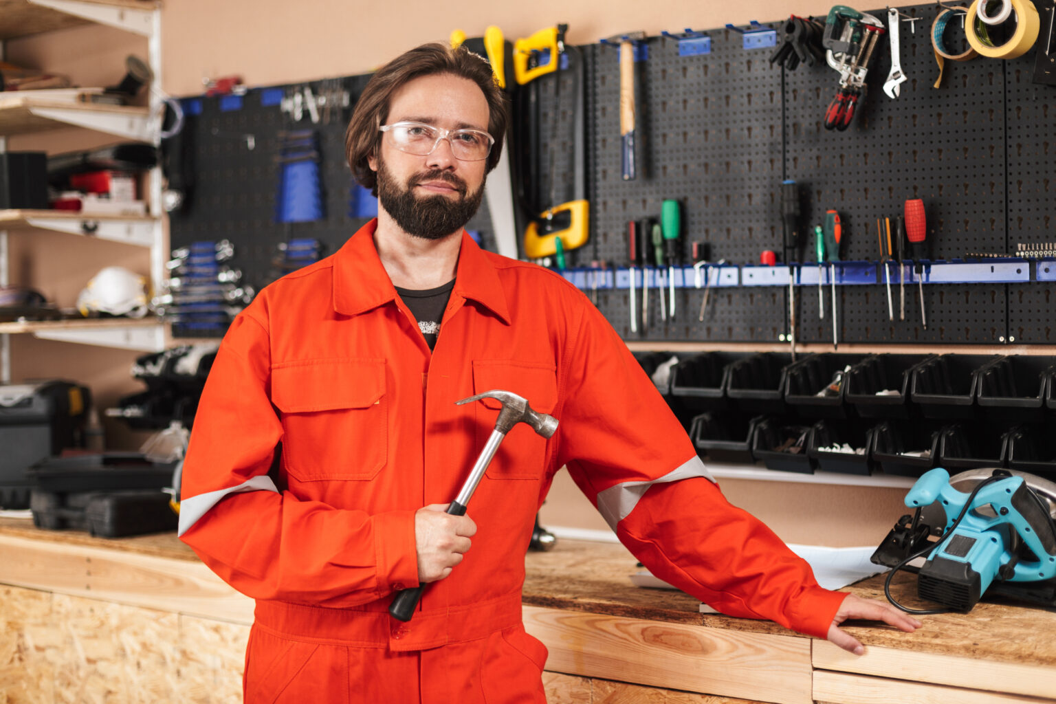 Foreman in orange work clothes and protective eyewear holding ha