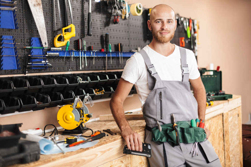 Smiling foreman in work clothes holding stapler in hand dreamily
