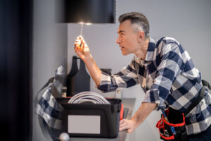 a handyman testing the voltage level of the range hood/extractor fan light